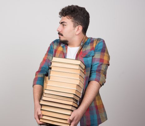Exhausted student with pile of books looking at somewhere. High quality photo